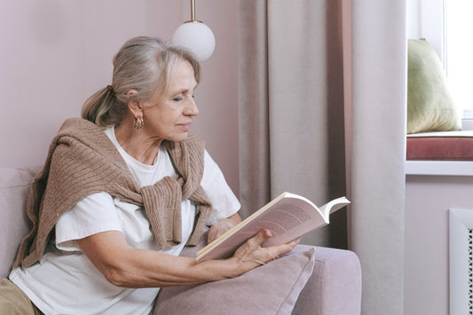 Ältere Frau sitzt auf dem Sofa und liest