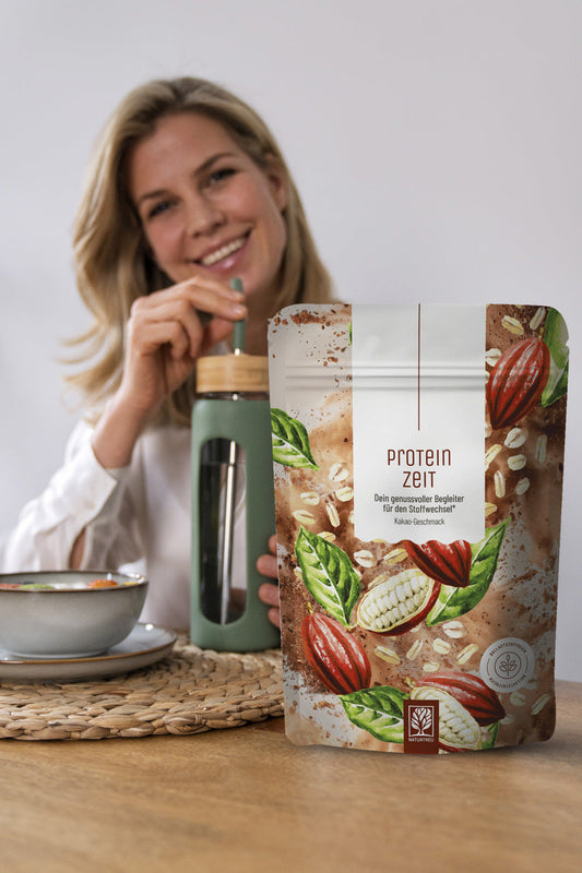 Im Vordergrund das Produkt Proteinzeit und dahinter eine lächelnde Frau