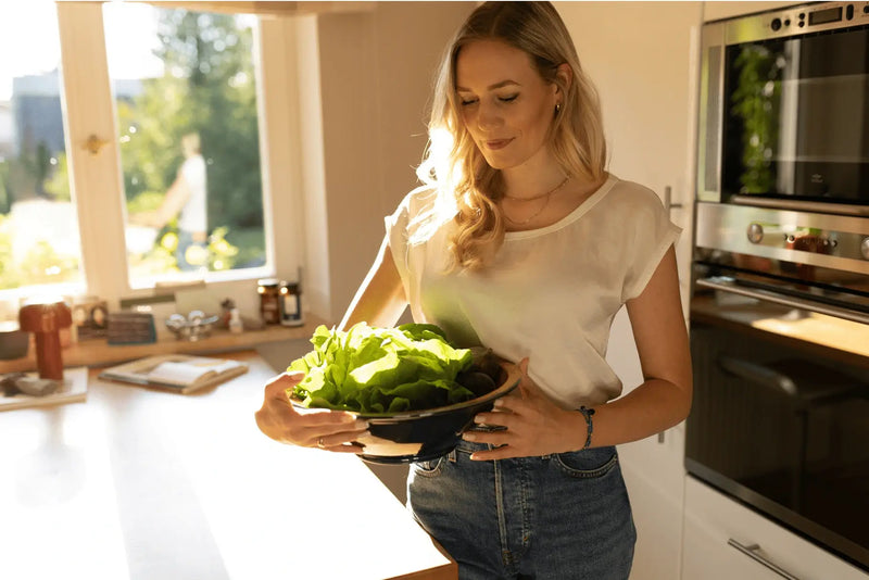 Gesundheits- und Ernährungsberaterin Saskia Johanna Rosenow steht in ihrer Küche. Sie hält eine Schüssel Salat in ihren Händen.